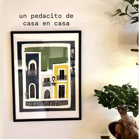 Framed artwork on a wall with a plant to the right